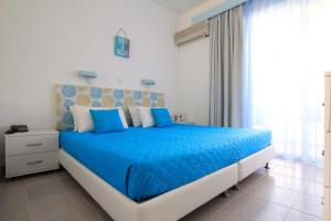 根纳迪克里斯蒂安娜公寓酒店的一间卧室配有一张带蓝色床单的床和一扇窗户。