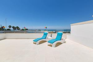 托雷拉皮罗Villa Belvedere by BarbarHouse的三个蓝白椅子坐在海滩庭院