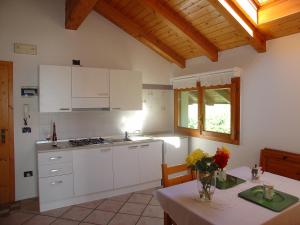 费德拉帕加内拉Casa Solaris的厨房配有白色橱柜和鲜花桌