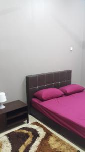 马六甲塔曼海岬西夏度假屋的一间卧室配有一张带紫色床单的床和一张桌子