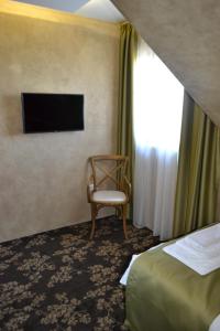 贝尔格莱德Garni Hotel Chicha - Winery ŠKRBIĆ的酒店客房设有椅子和电视。