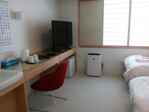 富士市西村酒店(Hotel Nishimura)的客房设有一张桌子、一台电视和一张床