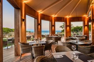 阿尔布费拉3HB Falésia Mar的餐厅设有桌椅,背景为大海