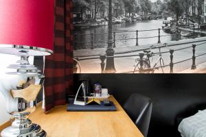 乌得勒支巴斯琛哥罗普酒店的一张桌子,上面有台灯和一张河画