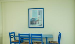 帕福斯Paphinia SeaView Apartments的一张蓝色的桌子和椅子,墙上挂着一张照片