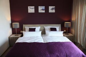 Gutenacker豪斯基普酒店的一间卧室配有一张大床,提供紫色床单和枕头