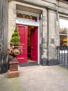 爱丁堡Six Brunton Place Guest House的前方有植物的建筑物的红色门