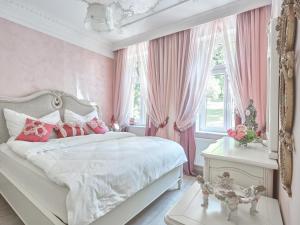玛丽亚温泉Apart House Plesia的卧室配有白色的床和粉红色窗帘