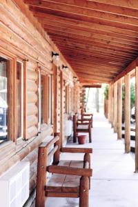 杜波依斯The Longhorn Ranch Resort Lodge & RV Park的坐在大楼门廊上的一排长椅