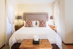 伊丽莎白港翠鸟旅馆的卧室配有一张白色大床和木桌