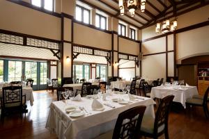 嬉野市汉密尔顿嬉野酒店的一间设有白色桌椅和窗户的用餐室