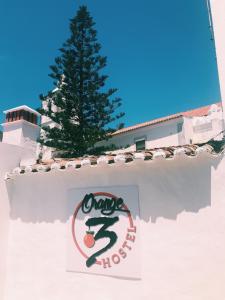 拉戈斯Orange3 Hostel的墙上的标志,后面有树