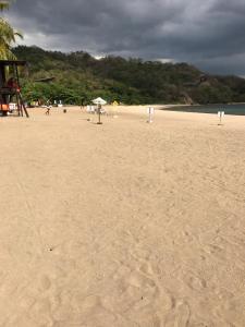 纳苏格布Pico Beach Front Condo的沙滩上,有雨伞,有人在沙滩上