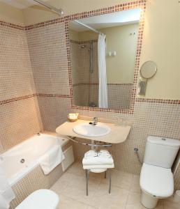 雷凯蒂奥米特罗库瓦酒店的一间带水槽、浴缸和卫生间的浴室