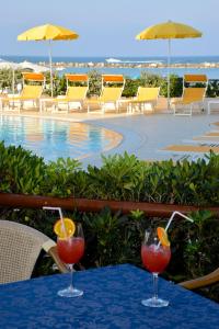 切塞纳蒂科Hotel David的游泳池畔的餐桌上供应的2杯鸡尾酒