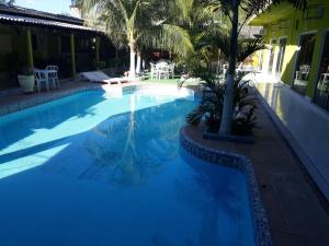 阿鲁阿南水瓶座旅馆的一座种植了棕榈树的蓝色游泳池,位于酒店大楼旁