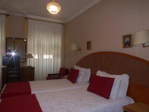 科英布拉拉贝罗酒店的酒店的客房 - 带红色和白色枕头的床