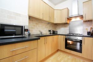 佩斯利Townhead Apartments Glasgow Airport的厨房配有木制橱柜、微波炉和烤箱。