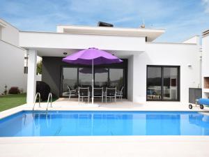 FamalicãoModern villa with private swimming pool的一座别墅,设有一座游泳池和一个紫色遮阳伞