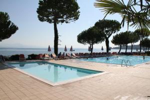 加达湖畔帕登赫戴尔拉戈度假酒店的游泳池,人们坐在椅子上,靠近大海