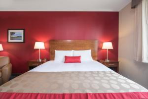 威利斯顿Bakken Airport XWA Hotel & Studios的酒店客房设有一张红色墙壁的大床