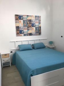 滨海波利尼亚诺House Mami的卧室配有蓝色的床和墙上的绘画作品