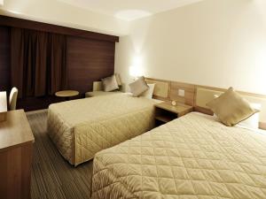 大阪UNIZO INN新大阪旅馆的酒店客房设有两张床和一张桌子。