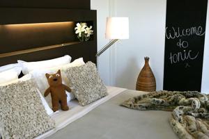 勒弗戴尔托尼克酒店的棕色泰迪熊坐在床上,床上有枕头