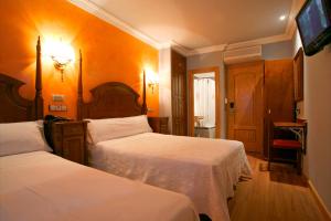 马德里维多利亚II旅馆的酒店客房设有两张床和电视。