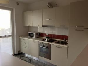 特伦托卡萨蓝博恩公寓的厨房配有白色橱柜、水槽和微波炉