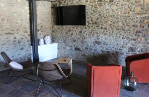 IsóbolMas Ravetllat的一间设有椅子和一台电视的石墙客房