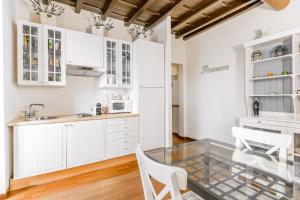 罗马Navona Bernini Lodge的厨房配有白色橱柜和玻璃桌