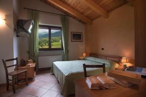 Paesana拉克莱塔酒店的一间卧室配有一张床、一张桌子和一个窗户。