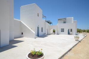 纳克索乔拉Apartments Naxos Camping的白色的房子,庭院里种有盆栽植物