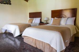 GuaillabambaEl Cano的酒店客房带两张床,带白色和棕色的床单。