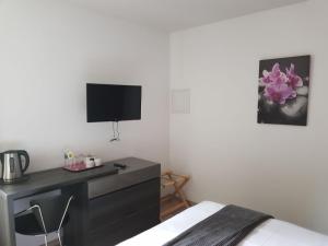 奥利韦Hotel Restaurant Pavillon Bleu的一间卧室配有一张床、一张书桌和一台电视。
