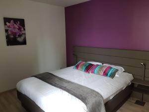 奥利韦Hotel Restaurant Pavillon Bleu的一间卧室配有一张紫色墙壁的床