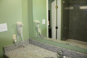 斯托克顿堡Deluxe Inn Fort Stockton的浴室水槽、吹风机和镜子