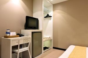 坤甸坤甸加亚马达酒店的一间设有床铺和墙上电视的房间