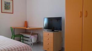 卡塔尼亚Fontanarossa Airport Apartment的一间卧室,配有带书桌的梳妆台和电视机