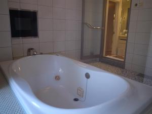 本庄市大酒店（仅限成人入住）的带淋浴的浴室配有白色浴缸。