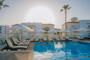 阿依纳帕New Famagusta Hotel & Suites的一座带椅子和遮阳伞的游泳池位于一座建筑旁边