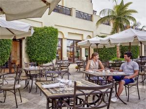 赫尔格达Steigenberger Aldau Beach Hotel的坐在户外餐厅的男女