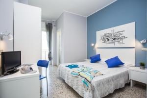 里米尼Hotel Tritone Rimini的一间卧室拥有蓝色的墙壁,配有一张带蓝色枕头的床。
