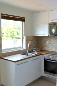 南泰利耶Room by Water的厨房配有白色橱柜、水槽和窗户。