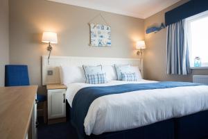 布莱克浦喜来登酒店的一间卧室配有一张带蓝白色床单的大床