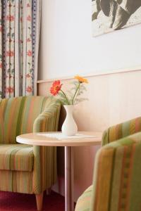 锡贝塔尔Hotel Silbertal的花瓶,桌子上花,两把椅子旁边