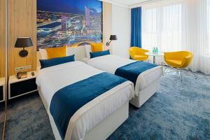 华沙华沙机场金色郁金香酒店的酒店客房带两张床和一张桌子以及椅子。