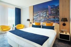 华沙华沙机场金色郁金香酒店的酒店客房设有一张大床,墙上挂有绘画作品