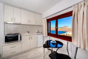 阿克罗蒂里阿斯帕拉索斯套房公寓的厨房配有白色橱柜、桌子和窗户。